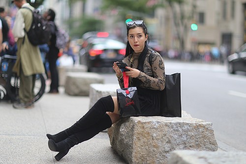 A woman checking her phone on 5th Avenue in front of St. Patrick's Cathedral.